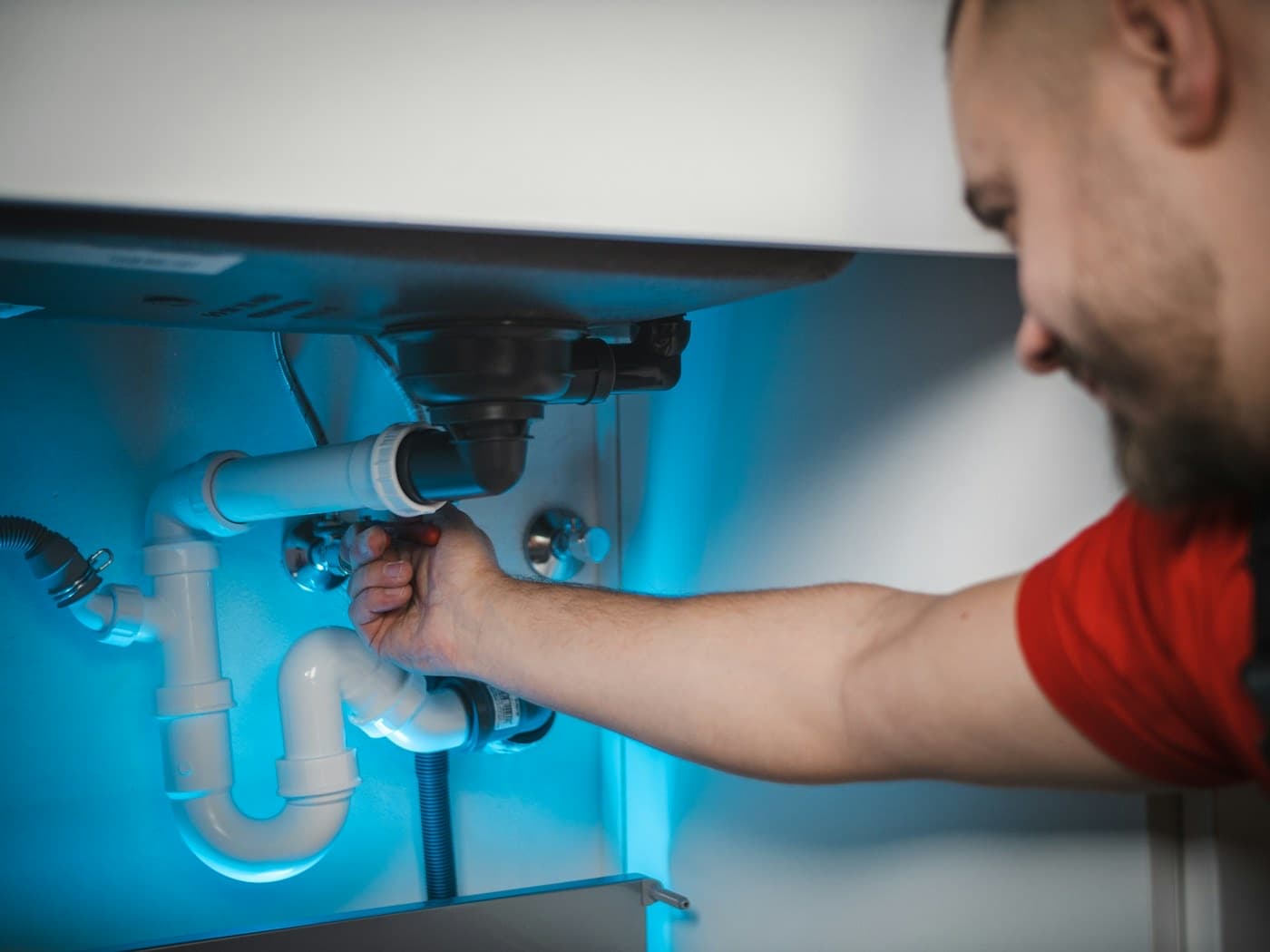 Lavabo altında tesisat kontrolü yapan usta